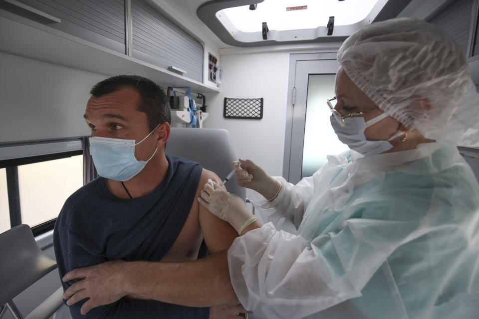 A medical worker administers a shot of Russia's Sputnik V coronavirus vaccine inside a mobile vaccination center in Krymsk, Krasnodar region, Russia, Friday, Oct. 29, 2021. Russia has recorded another record of daily coronavirus deaths even as authorities hope to stem contagion by keeping most people off work. Authorities have blamed soaring infections and deaths on Russia's lagging pace of vaccinations. About 51 million Russians — just over a third of the country's nearly 146 million people — were fully vaccinated as of Friday. (AP Photo/Vitaly Timkiv)