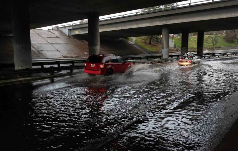 Motorists drive through a flooded section of Tuolumne Boulevard in Modesto, Calif., Saturday, Dec. 10, 2022.