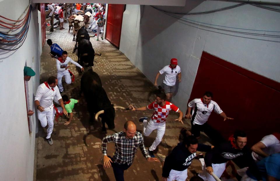 <p>La manada de toros, este lunes, en el cuarto encierro de San Fermín, a la entrada del callejón de la Plaza de Toros (Reuters) </p>