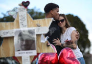 <p>Ashley Boul and Joel Robinson (L), who is an alumni of Marjory Stoneman Douglas High School, visit a makeshift memorial setup in front of the school on February 19, 2018 in Parkland, Fla. (Photo: Joe Raedle/Getty Images) </p>