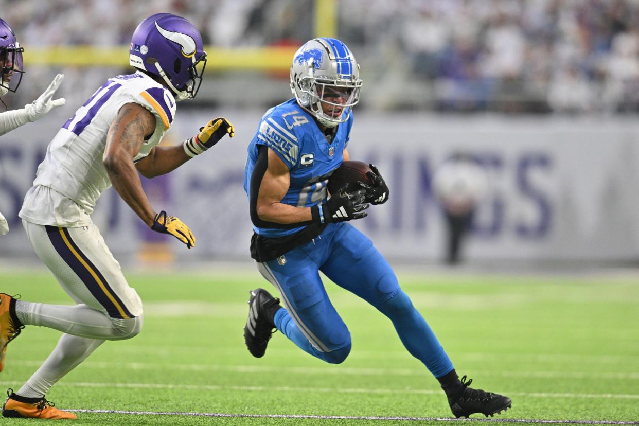 Detroit Lions receiver Amon-Ra St. Brown runs after the catch as Minnesota Vikings cornerback Akayleb Evans chases during the second quarter at U.S. Bank Stadium in Minneapolis on Sunday, Dec. 24, 2023.