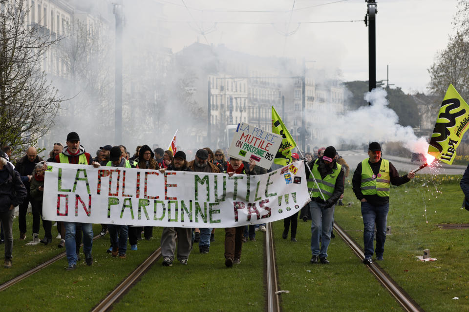 Workers demonstrate with a banner reading "Police mutilates, we don't forgive" Tuesday, March 28, 2023 in Nantes, western France. The fresh wave of strikes and protests is the 10th time since January that unions have called on workers to walk out and for demonstrators to flood the streets against Macron's push to move back France's legal retirement age from 62 to 64.(AP Photo/Jeremias Gonzalez)