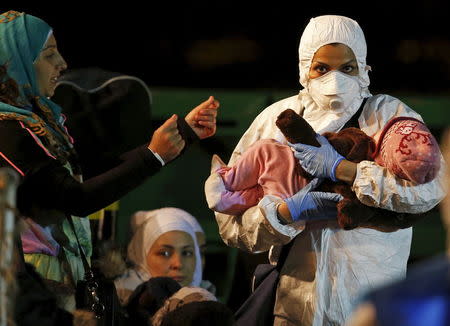 A child is carried by a rescue worker as he arrives with migrants on the boat at the Sicilian harbor of Pozzallo, April 19, 2015. REUTERS/Alessandro Bianchi