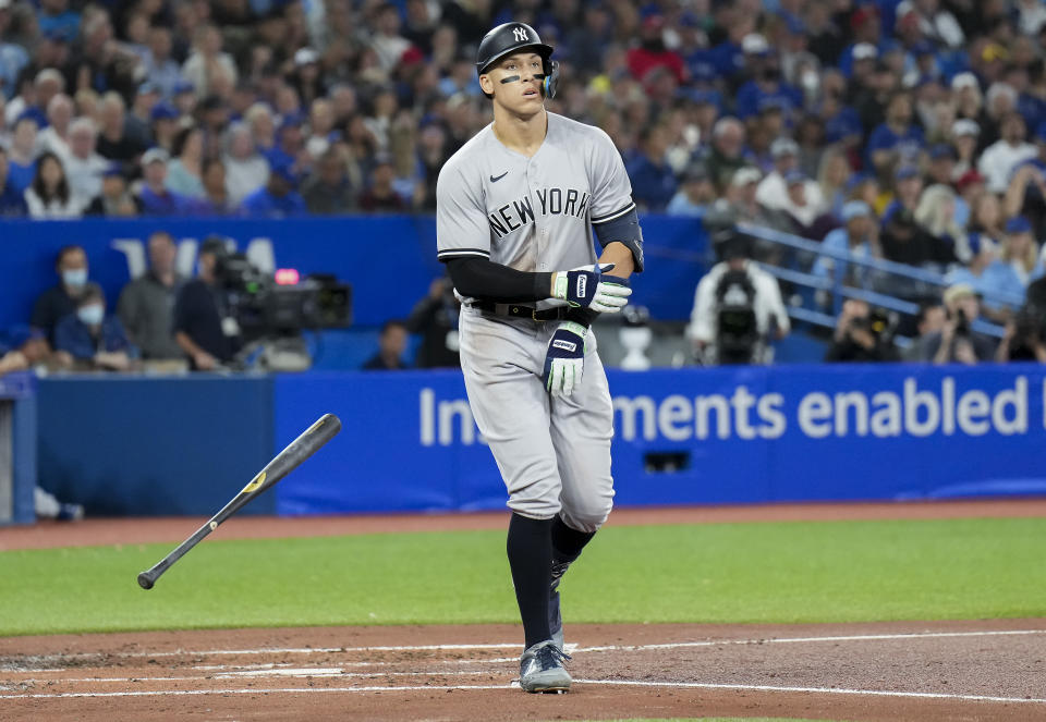 New York Yankees' Aaron Judge tosses his bat as he is walked by Toronto Blue Jays starting pitcher Kevin Gausman during third-inning baseball game action in Toronto, Monday, Sept. 26, 2022. (Nathan Denette/The Canadian Press via AP)