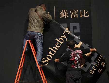 Workers install Sotheby's large banner on a wall during Sotheby's Beijing Art Week in Beijing, November 28, 2013. REUTERS/Kim Kyung-Hoon