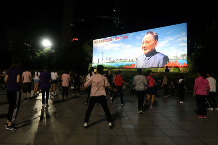 People dance in front of a picture of the former Chinese leader Deng Xiaoping ahead of the 40th anniversary of China's reform and opening up, at a square in Shenzhen, Guangdong province, China December 4, 2018. REUTERS/Thomas Suen