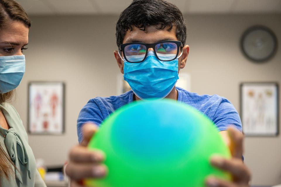 Physical therapy assistant Allison Sessa helps Kartik Bhakta maintain balance while working on a core strength exercise on Dec. 27, 2021, at Rehab Without Walls in San Antonio.