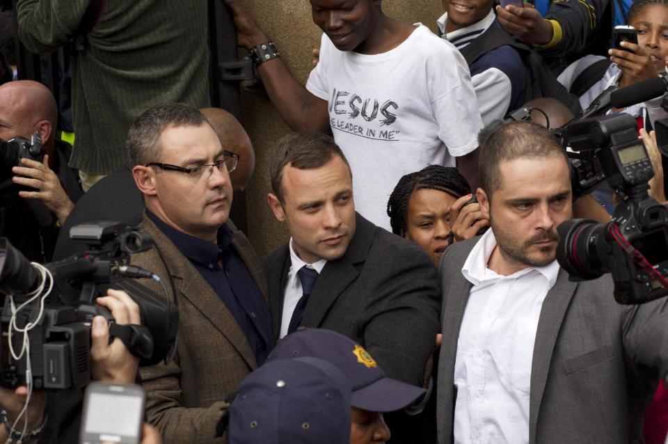 Oscar Pistorius, center, is escorted out by police officers as he leaves the high court on the second day of his trial in Pretoria, South Africa, Monday, March 3, 2014. Oscar Pistorius is charged with murder for the shooting death of his girlfriend, Reeva Steenkamp, on Valentines Day in 2013. (AP Photo/Themba Hadebe)