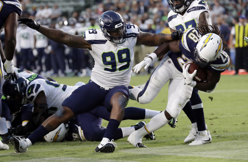 Los Angeles Chargers running back Melvin Gordon, right, scores a rushing touchdown past Seattle Seahawks defensive tackle Quinton Jefferson (99) during the first half of an NFL preseason football game Saturday, Aug. 18, 2018, in Carson, Calif. (AP Photo/Gregory Bull)