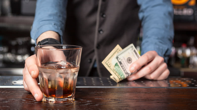 bartender with drink and cash