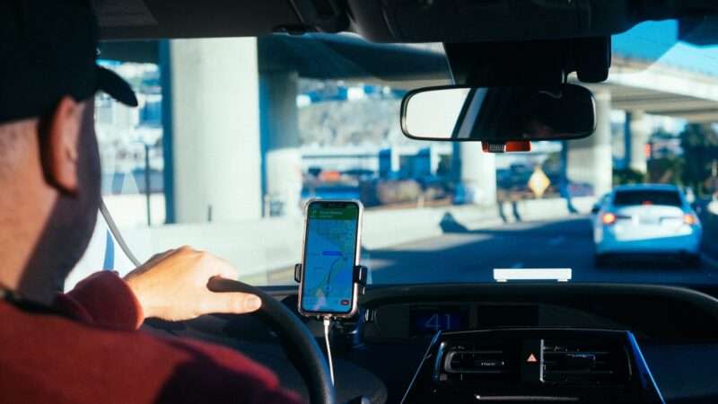 Someone drives car with a mounted smart phone showing a map