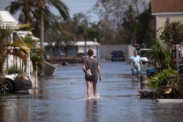 A resident of a mobile home park near Fort Myers Beach walks through floodwaters from Hurricane Ian on Sept. 29. Health officials in Florida are advising people to wear protective boots if entering the water, which can carry high levels of bacteria. (Photo: The Washington Post via Getty Images)