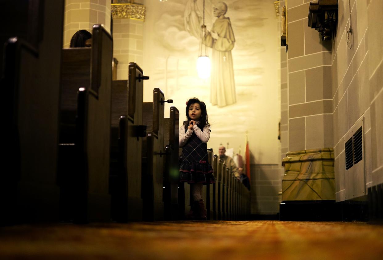 A young girl prays along with others during their Sunday Mass at a Polish Catholic church in Hamtramck, Mich., in January 2016. Several studies show that beginning in the early 2020s, young women are beginning to leave the church at higher rates than young men. Some worry about the long-term implications.