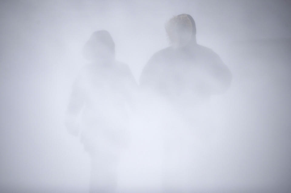 Angel Fuchs, left, and Marc Veillet enjoy a walk in Canal Park as the snow and wind picked up, Wednesday, Dec. 23, 2020 in Duluth, Minn. (Alex Kormann/Star Tribune via AP)