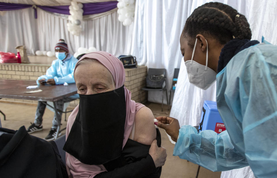 FILE - In this June 23, 2021, file photo, a teacher receives the single-dose Johnson & Johnson COVID-19 vaccine from a healthcare worker at Roshnee Civic Center, south of Johannesburg, South Africa. New infections in South Africa rose to record levels in recent days, part of a rapid rise across the continent, and experts say the surge here has not yet peaked. South Africa reimposed several restrictions, and its vaccination drive is finding its feet after several stumbles. But even as the campaign gathers pace, experts say it's too late to reduce the deadly impact of the current spike. (AP Photo/Themba Hadebe, File)