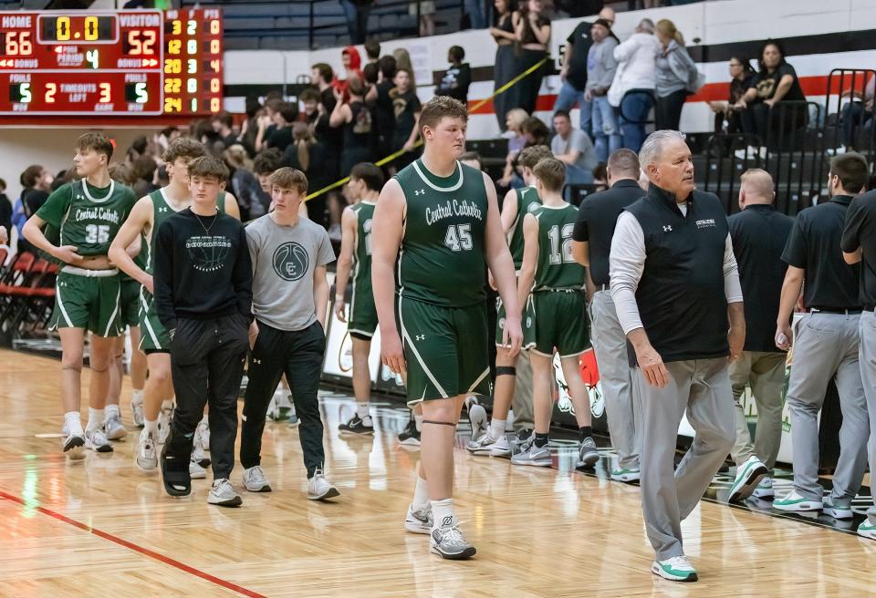Central Catholic’s Jonathan Stangl (45) and head coach Matt Creamer (right) lead the Crusaders off the court following their loss to Cardinal Mooney in a regional semifinal, Wednesday, March 13, 2024, at the Field House.