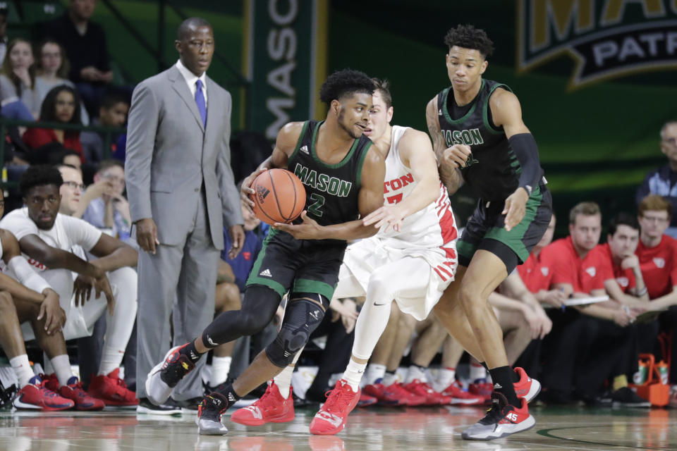 Dayton head coach Anthony Grant, left, watches as George Mason's Xavier Johnson (2) moves the ball on Dayton's Ryan Mikesell, center, as George Mason's Jordan Miller, right, follows during the first half of an NCAA college basketball game Tuesday, Feb. 25, 2020, in Fairfax, Va. (AP Photo/Luis M. Alvarez)