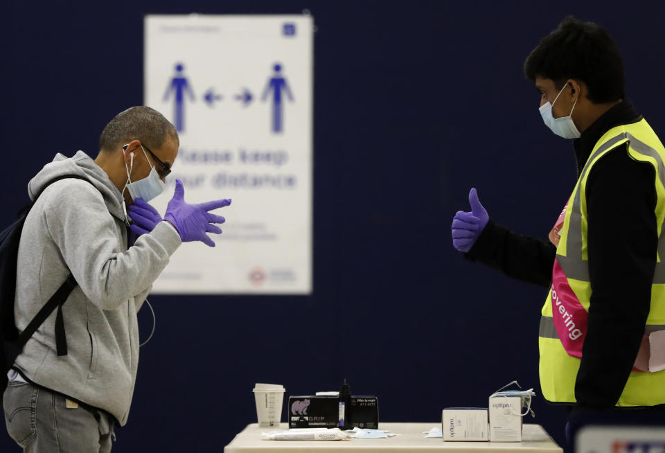 A London Underground worker, right, hands over a free face mask, gloves and hand sanitizer to a passenger at London's Baker Street station, Tuesday, June 9, 2020. Wearing a face mask will become compulsory on the London TFL public transport service starting from June 15, 2020, as a safety measure to contrast the COVID-19 pandemic. (AP Photo/Frank Augstein)