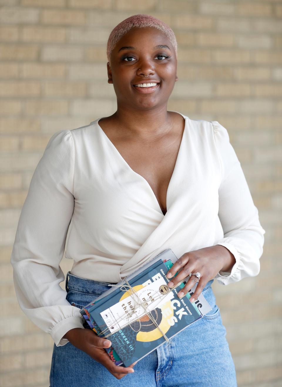Jasmine Settles holds a stack of books Tuesday, May 24, 2022, outside Crosstown Concourse in Memphis. Settles opened online bookstore Cafe Noir during the pandemic and is now planning to open a brick-and-mortar store and coffee shop.