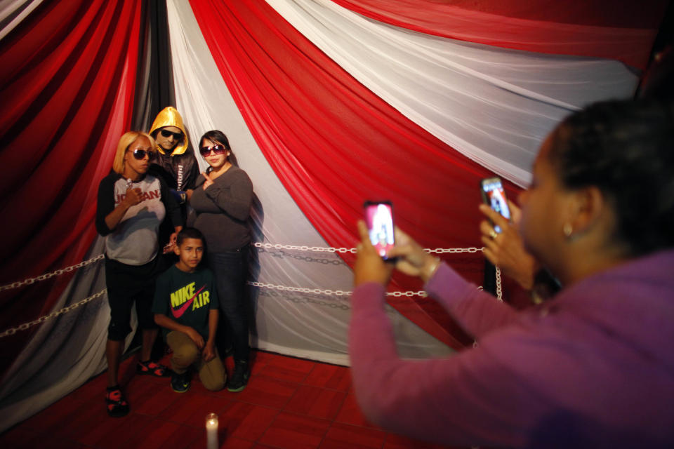 Lidianette Carmona, behind right, the wife of the late boxer Christopher Rivera, stands with Rivera's mother Celines Amaro, left, and Rivera's son Julio Christopher, as they pose for photos taken by fans with the body of Christopher Rivera propped up in a fake boxing ring during his wake at the community recreation center within the public housing project where he lived in San Juan, Puerto Rico, Friday, Jan. 31, 2014. Elsie Rodriguez, vice president of the Marin funeral home, explained that Rivera had asked his family that if he died, he wanted his funeral to make reference to his boxing career. (AP Photo/Ricardo Arduengo)