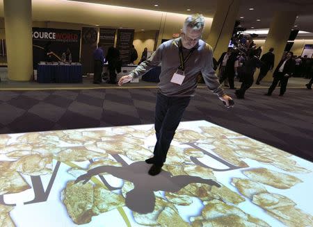Exhibitor Dale Michaud walks on a projected gold display at the Prospectors and Developers Association of Canada (PDAC) trade show in Toronto in this March 6, 2011 file photo. REUTERS/Mike Cassese/Files