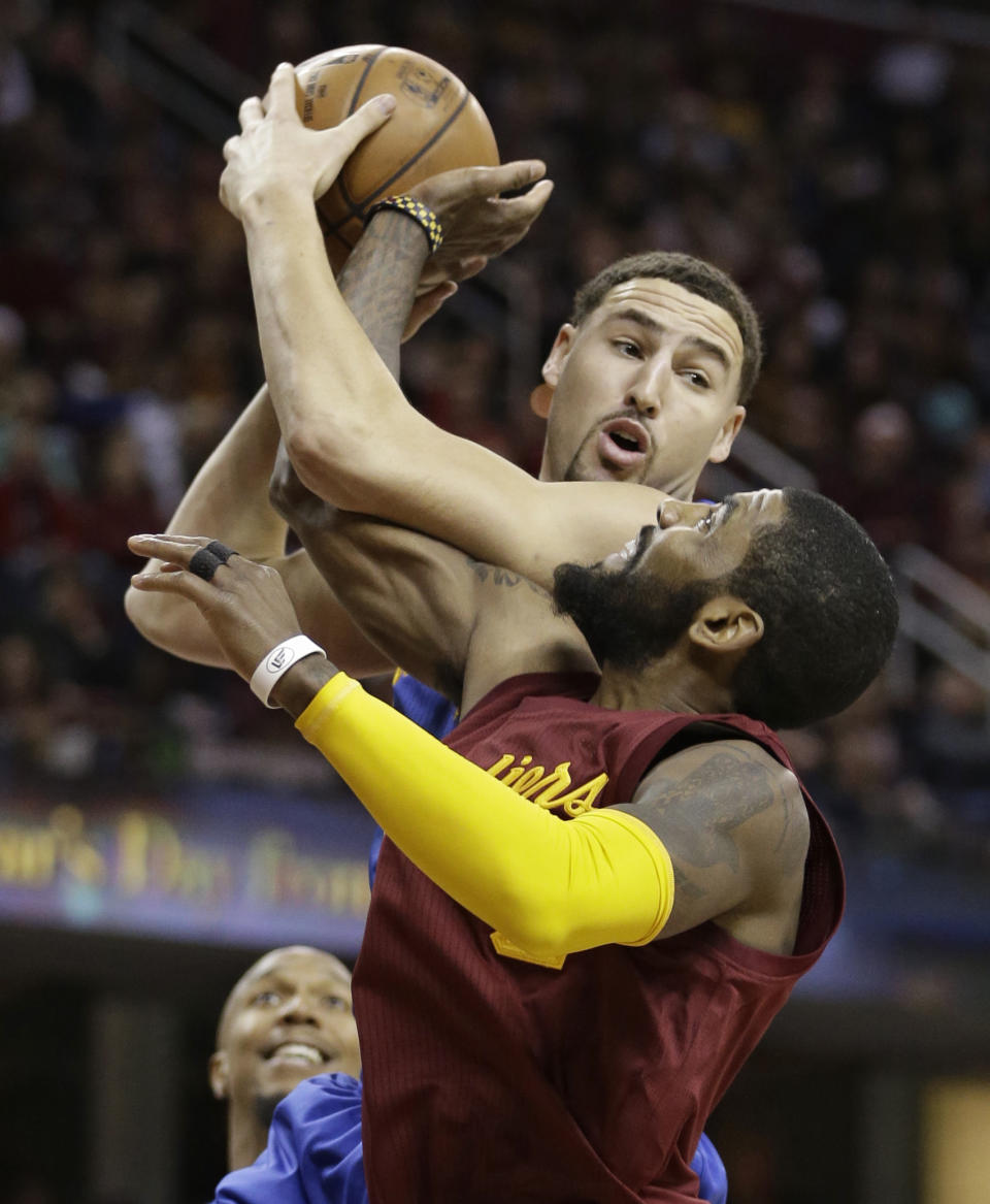 Golden State Warriors' Klay Thompson looks to pass over Cleveland Cavaliers' Kyrie Irving, right, in the first half of an NBA basketball game, Sunday, Dec. 25, 2016, in Cleveland. (AP Photo/Tony Dejak)
