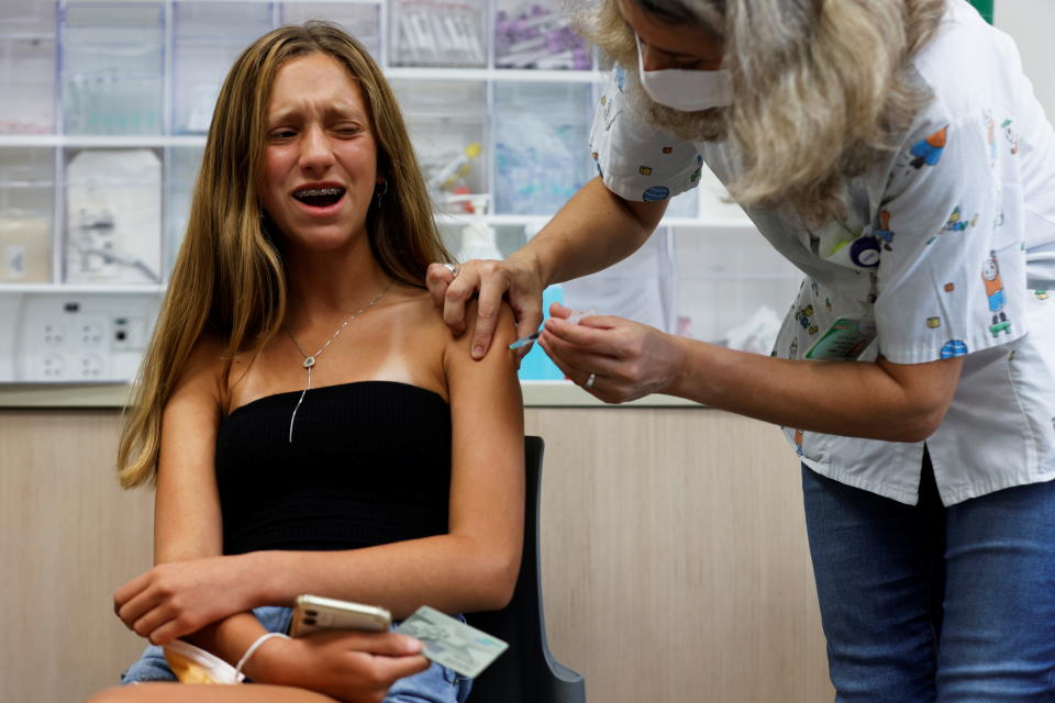 A teenager reacts while receiving a dose of a vaccine against the coronavirus disease (COVID-19) as Israel urged more 12- to 15-year-olds to be vaccinated, citing new outbreaks attributed to the more infectious Delta variant, at a Clalit healthcare maintenance organisation in Tel Aviv, Israel June 21, 2021. REUTERS/Amir Cohen