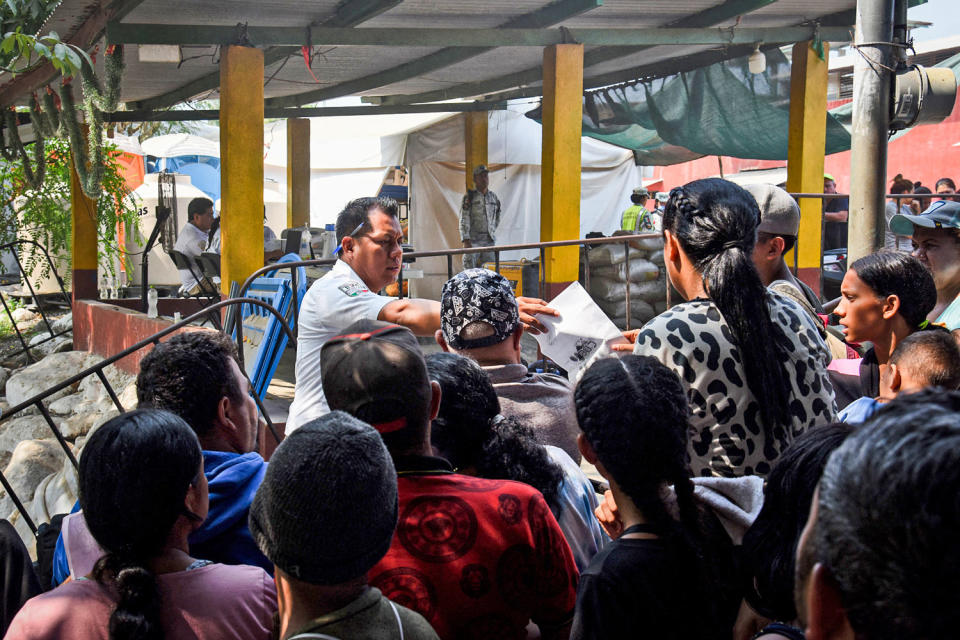 Migrants hand over their documents to government officials. (Isaac Guzman / AFP via Getty Images)