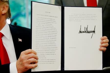 U.S. President Donald Trump displays an executive order on immigration policy after signing it in the Oval Office at the White House in Washington, U.S., June 20, 2018. REUTERS/Leah Milllis