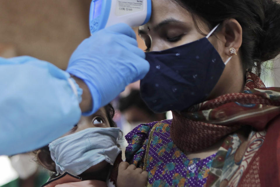 A child looks at his mother being screened for COVID-19 symptoms at an apartment complex in Mumbai, India, Tuesday, July 28, 2020. (AP Photo/Rajanish Kakade)