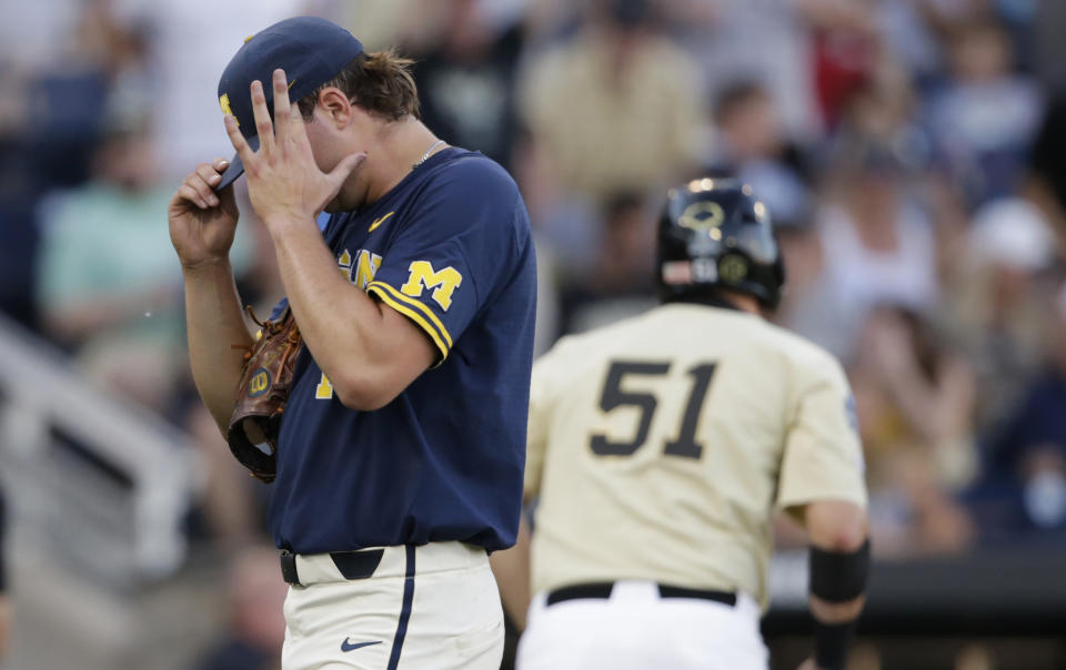 Michigan pitcher Jeff Criswell, left, adjusts his cap as he walks to the dugout after the fourth inning of Game 3 of the NCAA College World Series baseball finals against Michigan in Omaha, Neb., Wednesday, June 26, 2019. (AP Photo/Nati Harnik)