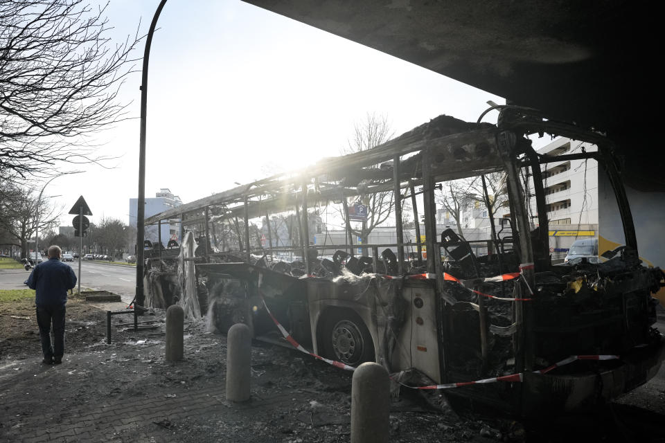 A burned-out bus stands partly beneath a residential building in the district Neukoelln in Berlin, Germany, Tuesday, Jan. 3, 2023. People across Germany on Saturday resumed their tradition of setting off large numbers of fireworks in public places to see in the new year. The bus was set on fire during the New Year's celebrations. (AP Photo/Markus Schreiber)