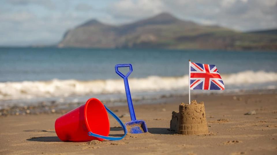 Union Jack flag on a castle shaped sandcastle on a beautiful beach with shining sunshine