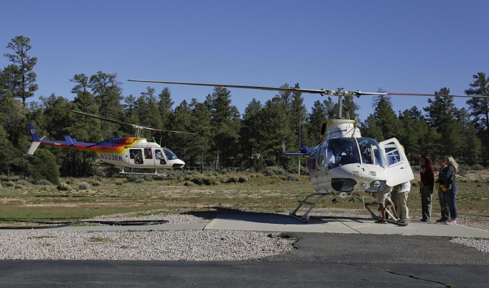 FILE - In this Oct. 4, 2013 file photo, tourists board a helicopter for a tour over Grand Canyon National Park, in Tusayan, Ariz. The fees for air tour operators that use technology to quiet the sound of aircraft at Grand Canyon National Park have been reduced. The new $20 fee per flight took effect Jan. 1, 2014, for any of eight operators authorized to take visitors sightseeing over the massive gorge. Operators that don't have the technology considered to be quiet will continue to pay $25 per flight. (AP Photo/Julie Jacobson)