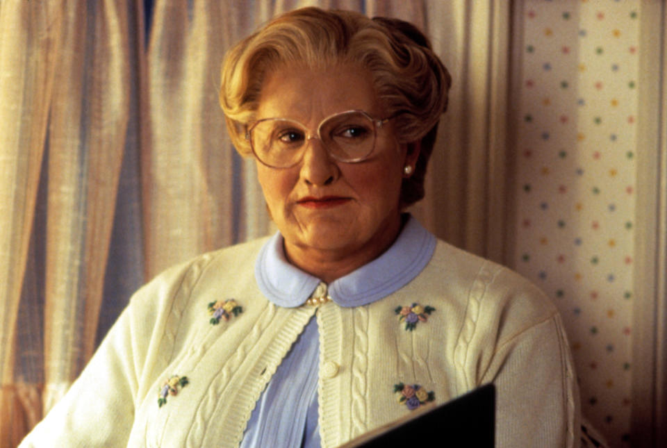 Robin Williams dressed as an older woman in a wig, glasses, and cardigan to be Mrs Doubtfire