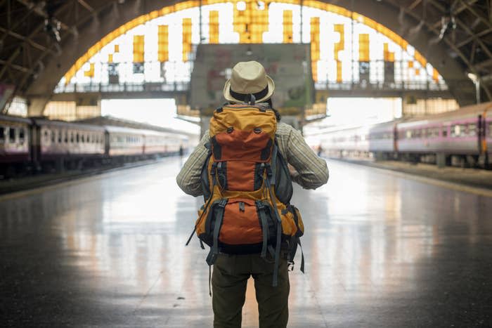 Traveler man waits train on railway platform.