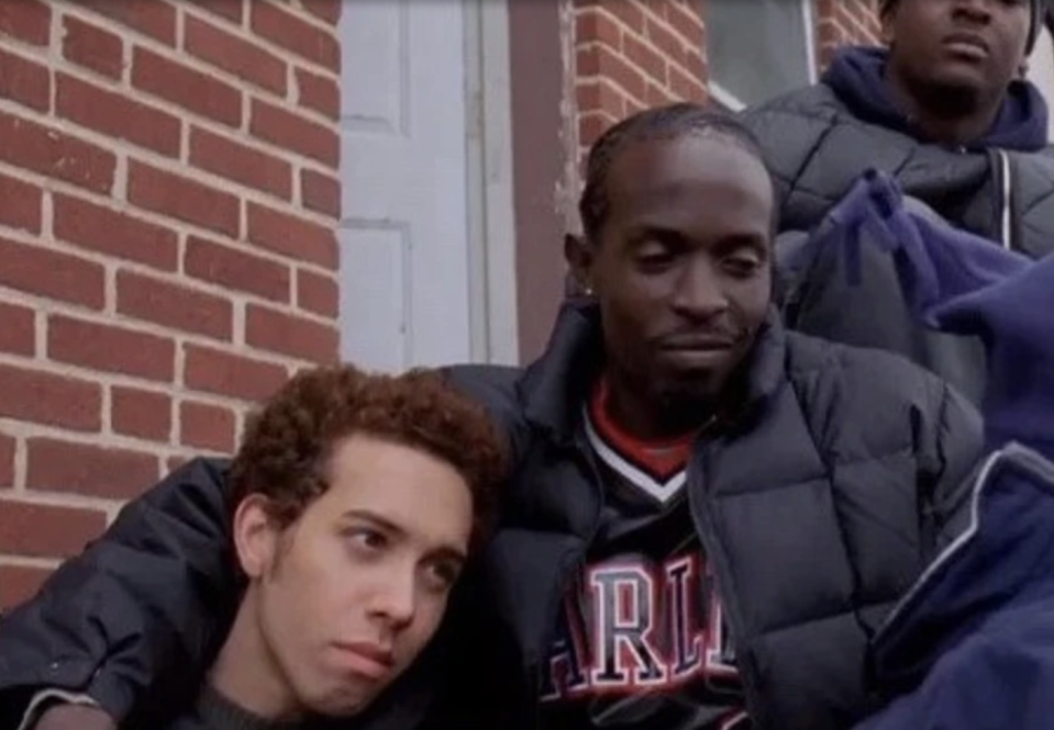 Two characters from the TV show 'The Wire', with one resting his head on the other's shoulder