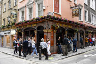 People stand outside a pub in Soho, as the capital is set to reopen after the lockdown due to the Coronavirus outbreak, in London, Saturday, July 4, 2020. England is embarking on perhaps its biggest lockdown easing yet as pubs and restaurants have the right to reopen for the first time in more than three months. In addition to the reopening of much of the hospitality sector, couples can tie the knot once again, while many of those who have had enough of their lockdown hair can finally get a trim. (AP Photo/Alberto Pezzali)