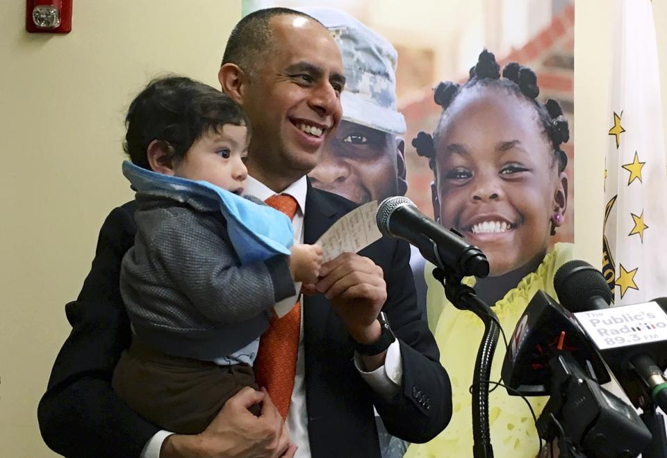 In this March 20, 2019, photo, Mayor Jorge Elorza holds his son Omar during a news conference in Providence, R.I. Elorza's decision to frequently take his son to work with him has brought praise from some who say he's a role model, but also raised questions about whether he has taken it too far. (Steve Klamkin/WPRO News via AP)