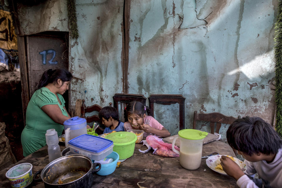 Los tres hijos de Consuelo Pascacio, Estiben, de 4; Estefany, de 11, y Javier, de 14, comen un estofado de arroz con pollo que recogió en una olla comunitaria, en su casa en el barrio Nueva Esperanza de Lima, Perú, el lunes 8 de junio de 2020. (AP Foto/Rodrigo Abd)