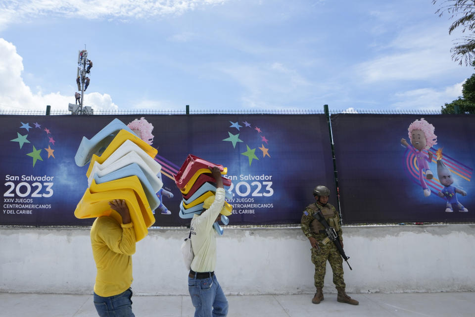 FILE - A soldier stands guard as workers complete the finishing touches at the newly remodeled Jorge 'El Magico' Gonzalez stadium, a day ahead of the Central America and Caribbean Games opening ceremony, in San Salvador, El Salvador, June 22, 2023. The largest international event here since President Nayib Bukele's government entered an all-out war against gangs, the games is drawing athletes from 35 countries across the region. (AP Photo/Arnulfo Franco, File)