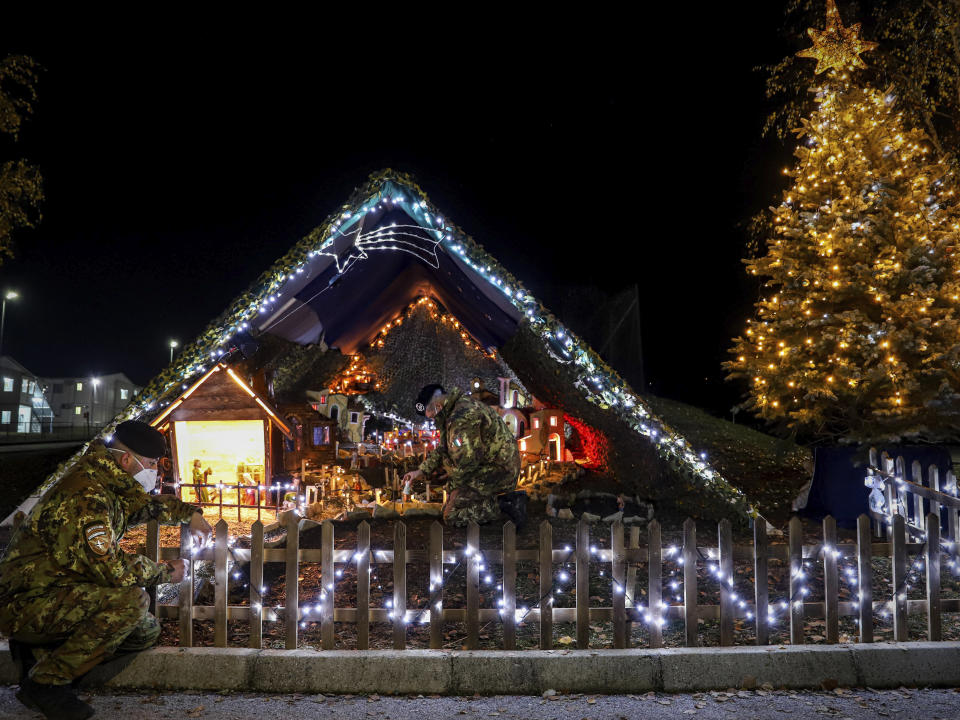 In this photo provided by NATO-led peacekeeping mission in Kosovo (KFOR), Italian soldiers decorate lights on the Christmas Eve in the KFOR military headquarters in Kosovo capital Pristina, Thursday, Dec. 24, 2020. The coronavirus pandemic has totally changed Christmas time operation method and celebrations for the Kosovo Force but it has left unchanged its mission: keeping Kosovo safe and secure for 22 years now on. (KFOR via AP)