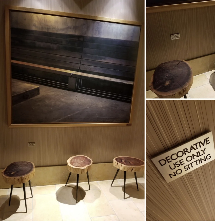 Framed photo of wooden benches above three wooden stools. Sign reads: "Decorative use only, no sitting."