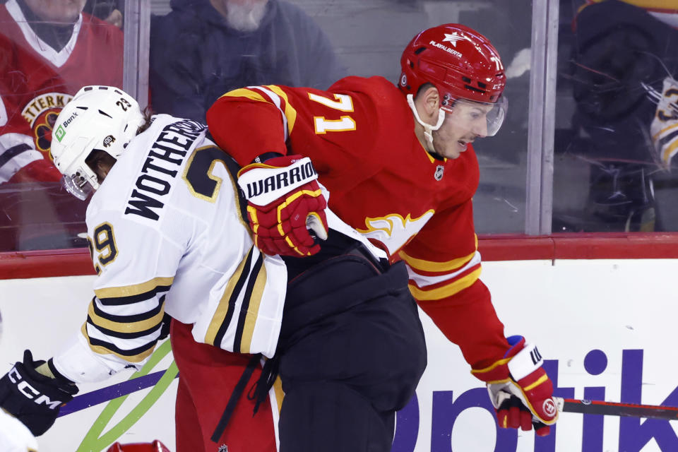 Boston Bruins' Parker Wotherspoon, left, battles with Calgary Flames' Walker Duehr during the first period of an NHL hockey game Thursday, Feb. 22, 2024, in Calgary, Alberta. (Larry MacDougal/The Canadian Press via AP)