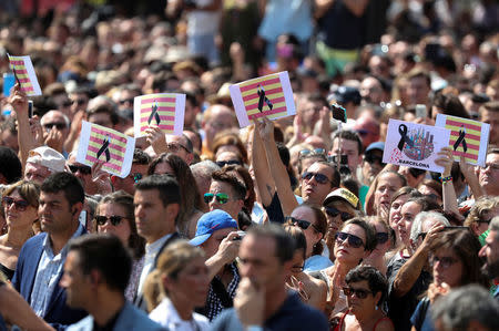 People hold up placards depicting Catalan flag with a black ribbon as they observe a minute of silence in Placa de Catalunya, a day after a van crashed into pedestrians at Las Ramblas in Barcelona, Spain August 18, 2017. REUTERS/Sergio Perez