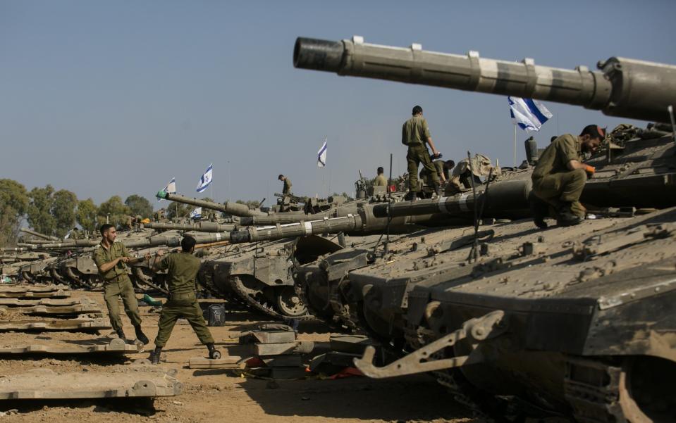 Tanks flying the Israeli flag line up after returning from operations inside Gaza