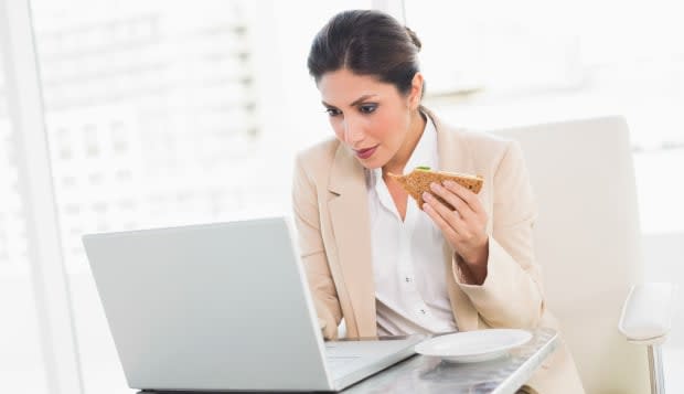 Focused businesswoman eating lunch as she is working at the office