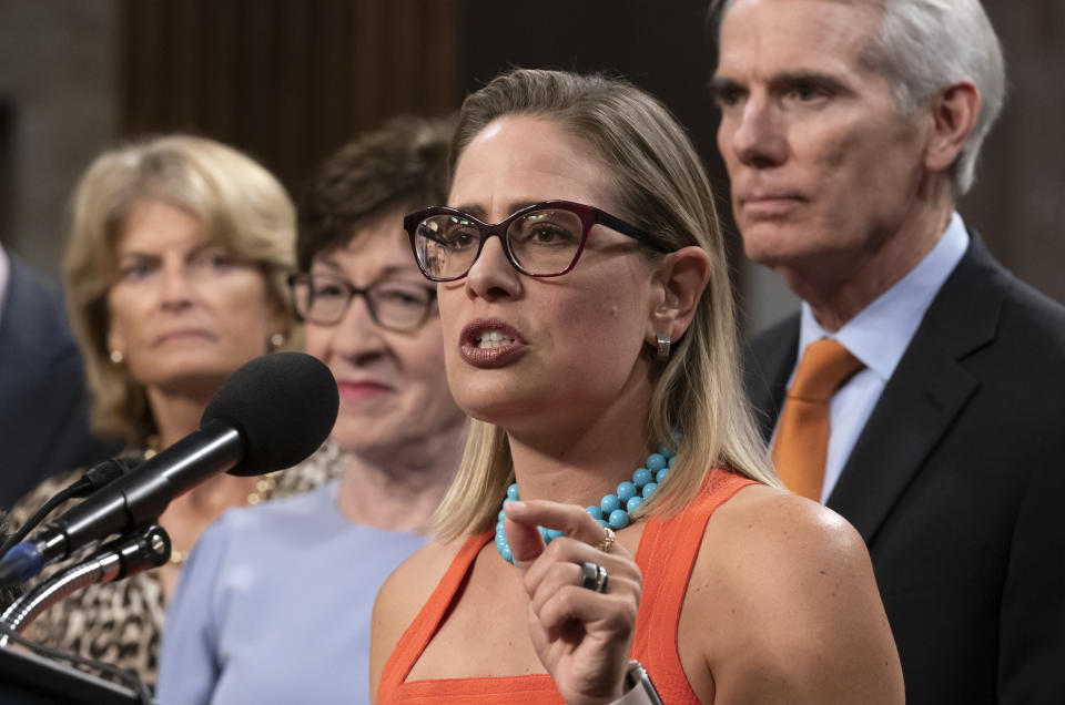 FILE - Sen. Kyrsten Sinema, D-Ariz., center, gestures during a news conference at the Capitol in Washington, July 28, 2021, while working on a bipartisan infrastructure bill with, from left, Sen. Lisa Murkowski, R-Alaska, Sen. Susan Collins, R-Maine, and Sen. Rob Portman, R-Ohio. Though elected as a Democrat, Sinema announced Friday, Dec. 9, that she has registered as an Independent, but she does not plan to caucus with Republicans, ensuring Democrats will retain their narrow majority in the Senate. (AP Photo/J. Scott Applewhite, File)