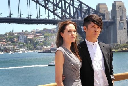 Actress Angelina Jolie and cast member Miyavi pose in front of Sydney Harbor Bridge after a news conference for new film "Unbroken", November 18, 2014. REUTERS/Patrick Riviere