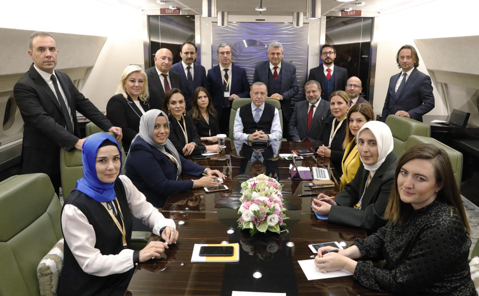 In this photo taken late Tuesday, Oct. 22, 2019, Turkish President Recep Tayyip Erdogan poses for photos with Turkish journalists in his plane on his way back from Russia, near Ankara, Turkey. Russia and Turkey reached an agreement that would cement their power in Syria, deploying their forces across nearly its entire northeastern border to fill the void left by President Donald Trump's abrupt withdrawal of U.S. forces. (Presidential Press Service via AP, Pool )